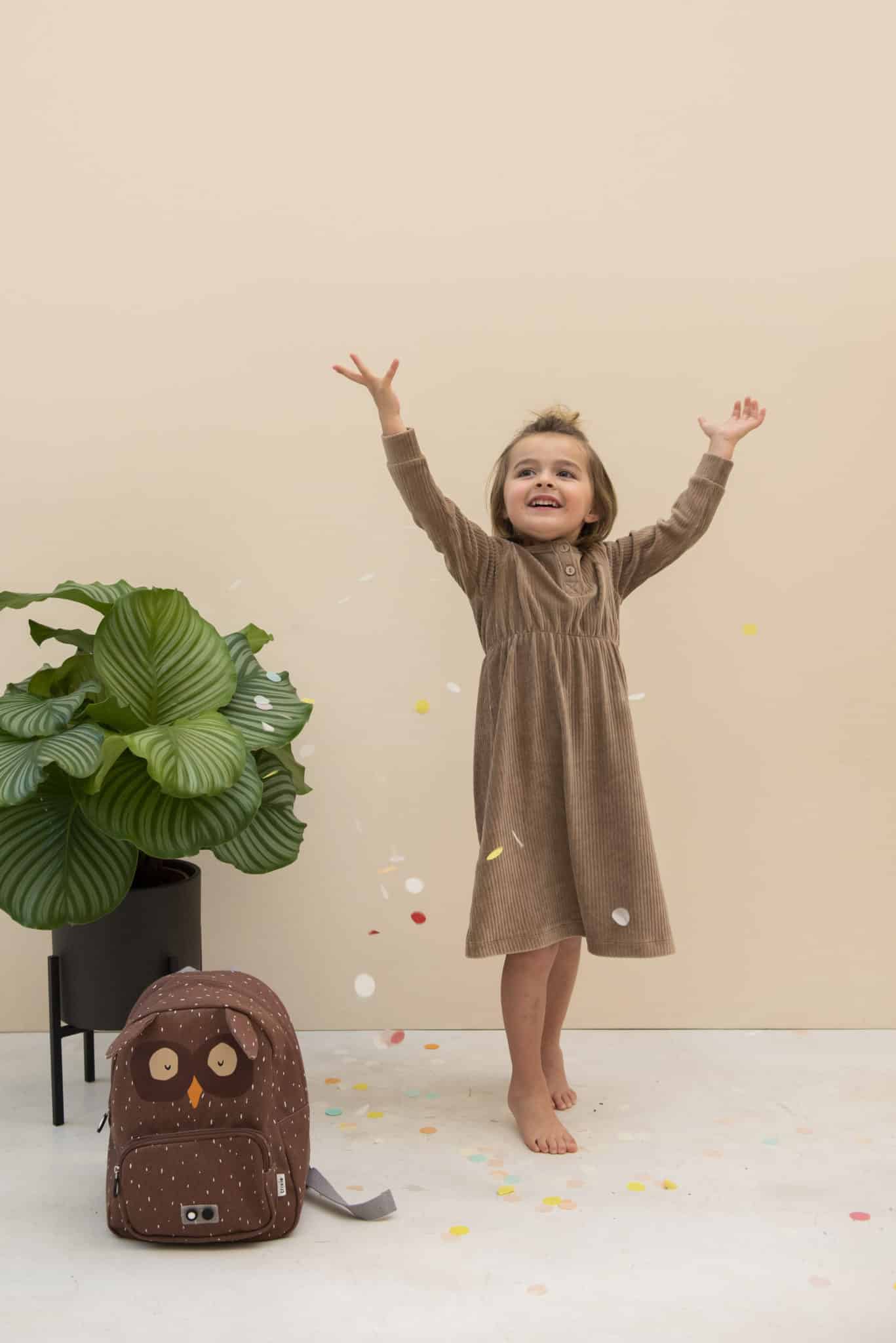 Child Throwing Confetti Next to Owel Bag