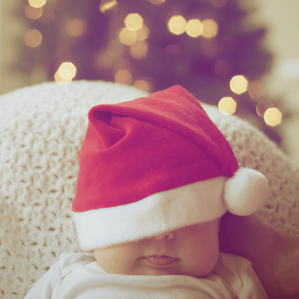 babys face covered in Christmas hat
