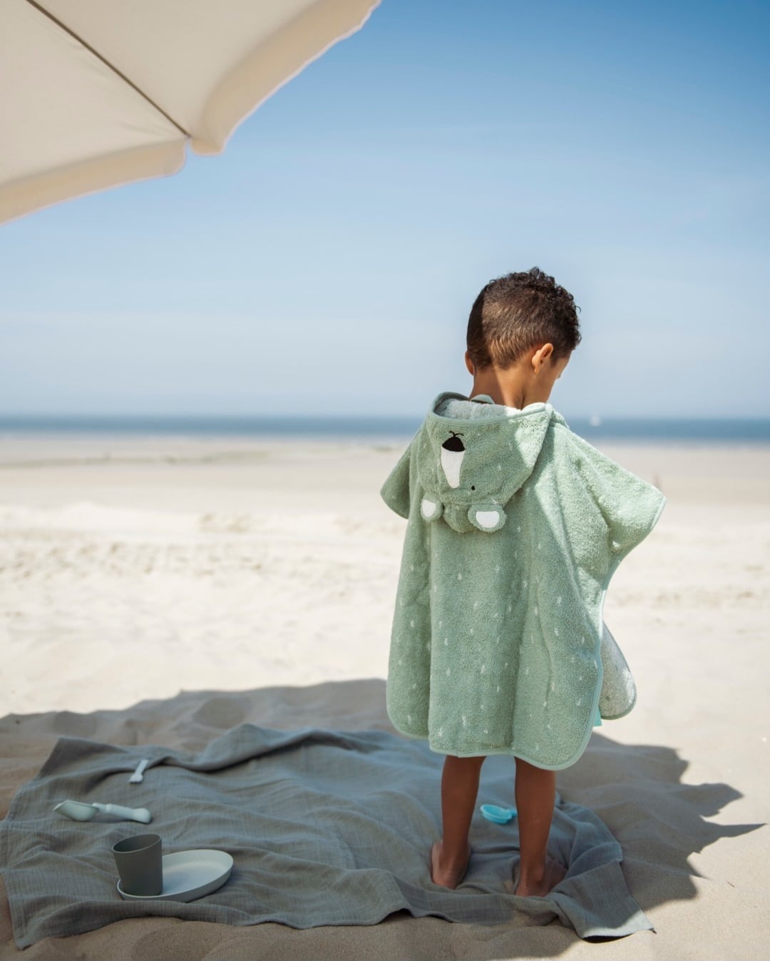 child wearing hooded polar bear towel on the beach