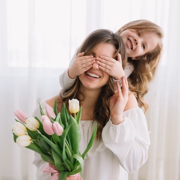child covering mothers eyes with flowers